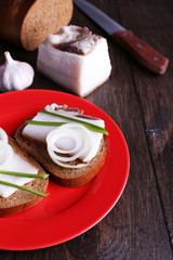 Sandwiches with lard on plate and garlic on wooden background