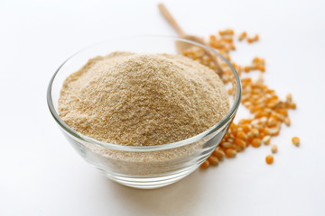 Glass bowl with flour and corn grains isolated on white