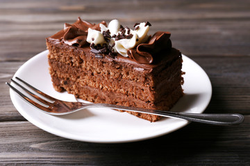 Tasty piece of chocolate cake on wooden table background