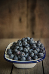 Blueberries in rustic kitchen setting with old wooden background