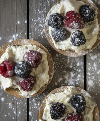Fresh fruit tartlets on rustic wooden kitchen background