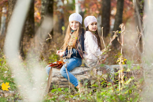 Two Beautiful girls wearing a beret sitting on log posing