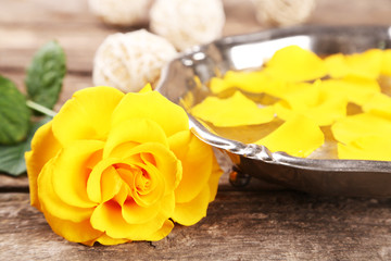 Rose flower and petals in bowl on wooden background