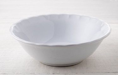 Empty white ceramic bowl on white wood