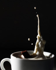 chocolate falling in milk and milk splashing out of a cup