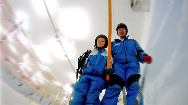 Son with father rise on skilift in yearround ski complex