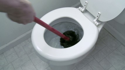 Using a plunger in an attempt to unclog a toilet.  Two clips with clean water in the bowl.