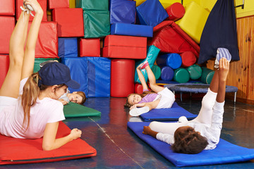 Kinder turnen im Kindergarten mit Erzieherin