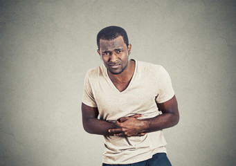 Man with stomach pain on gray wall background 