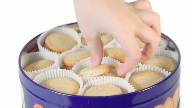 Kids hand takes cookies from metal box but then puts it back