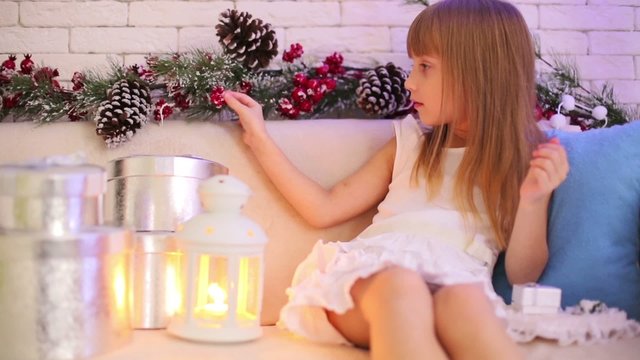 Little girl sitting on the sofa with Christmas gifts