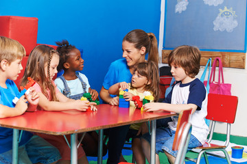 Kinder sitzen mit Erzieherin im Kindergarten