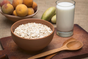 Bowl of rolled oats with glass of milk and peaches
