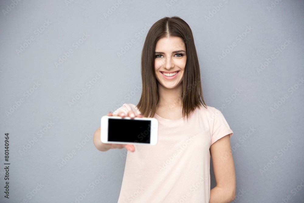 Canvas Prints Smiling young woman showing blank smartphone screen