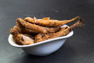 Frittierter, sauerer Stint mit Panade umhüllt. Serviert in weißem Schälchen.