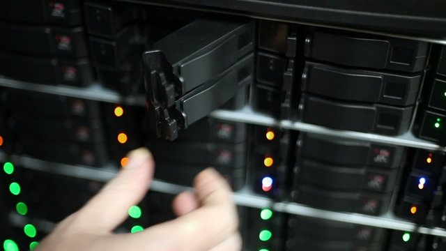 Hand opens doors of boxes for hard drives at data server rack