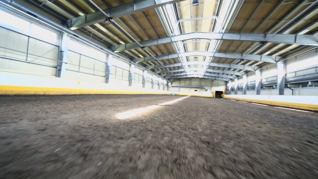Empty indoor horse riding hangar with ground covering