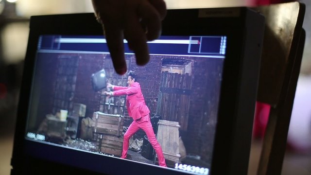 Monitor where man in pink suit slowly throw TV on the floor