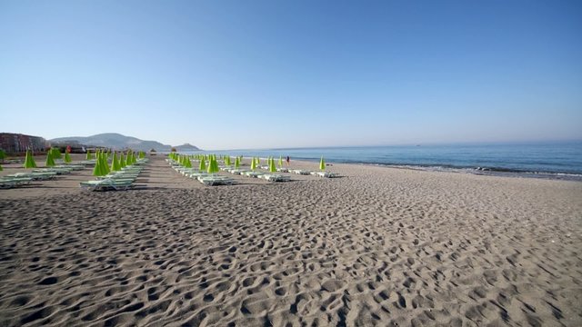 Empty beach with rows of couches and folded umbrellas