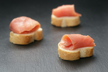 baguette slices with curred salmon on slate background
