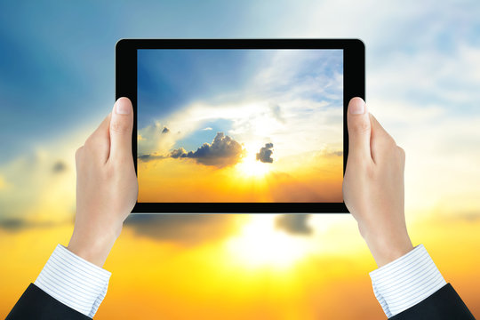 Businessman hands holding tablet pc,taking photo of twilight sky