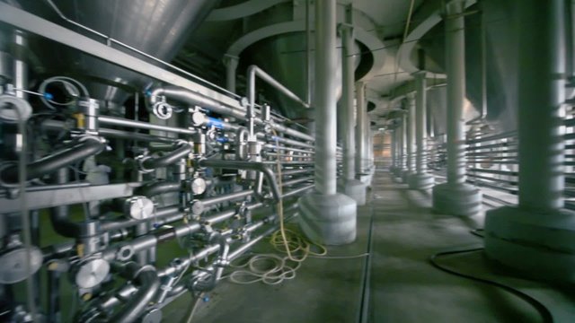 Huge reservoirs and piping in workshop of brewery, panoramic motion