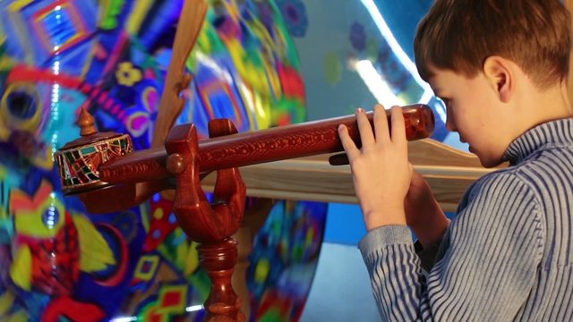 Little boy looking in wooden tube to whirling kaleidoscope