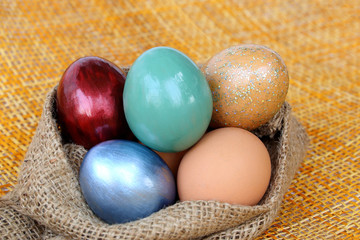 Colorful easter eggs in burlap hessian sacking bag.