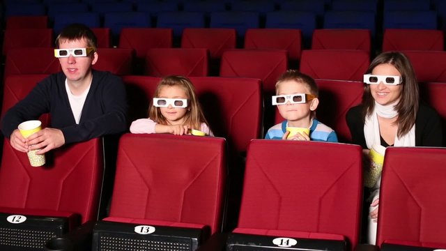 Family of four people resting together in a modern 3D cinema