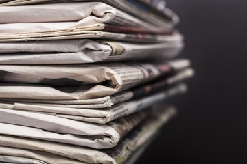 Journalism. Stack of newspapers on black background