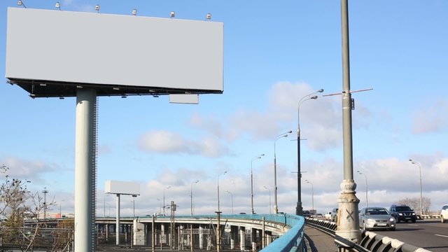 Road with moving cars and big blank billboard at sunny day