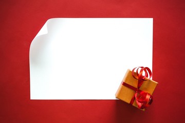 Background. Christmas sheet of paper with small gift on red