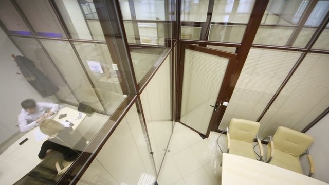 Top view of white table and chairs in small lit meeting room
