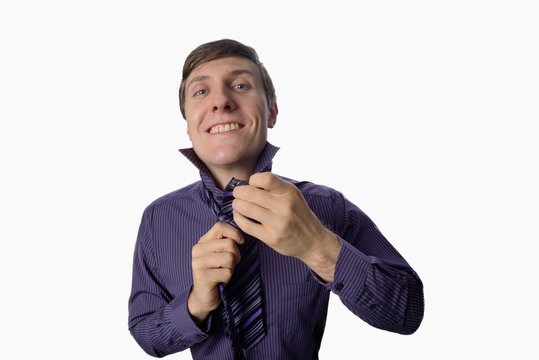 Young man who tries to tie one tie on white background