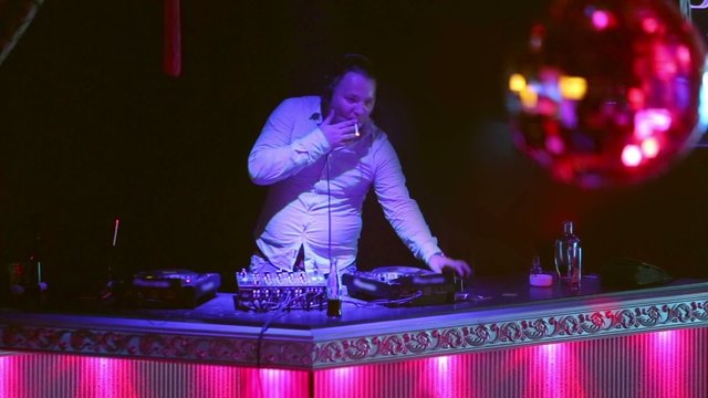 DJ lights and smokes cigarette at his workplace in nightclub