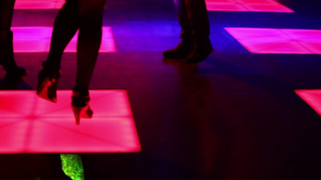 Three women and one man dance in night club