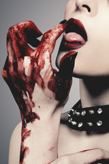 Obraz premium Sexy young woman licks blood against grey background