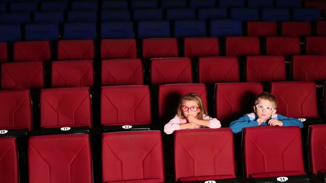 Boy and girl sitting alone in the cinema and watching a movie