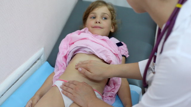 woman doctor surveys hands little girl lying on couch