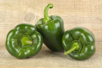 Studio shot of green bell peppers on wooden plank