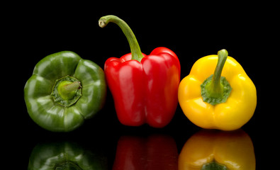Red,green,yellow bell peppers isolated on black
