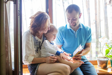 Obraz premium Happy family sitting on a windowsill and read a book.