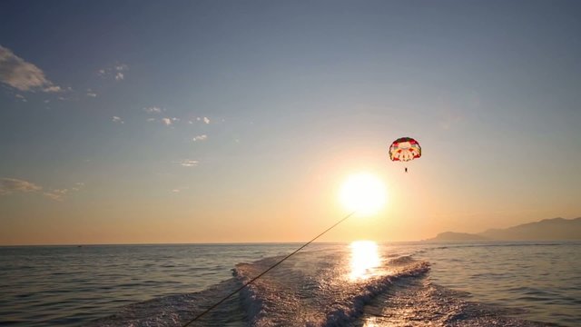 Glider flies over sea at sunny summer evening and traces of boat