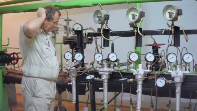 Man watches reading of several manometers on tubes and scratching his head in thought