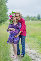 Happy pregnant couple hugging in nature