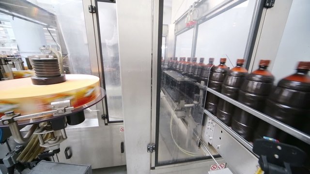 Many brown bottles moving on conveyor on labeling line