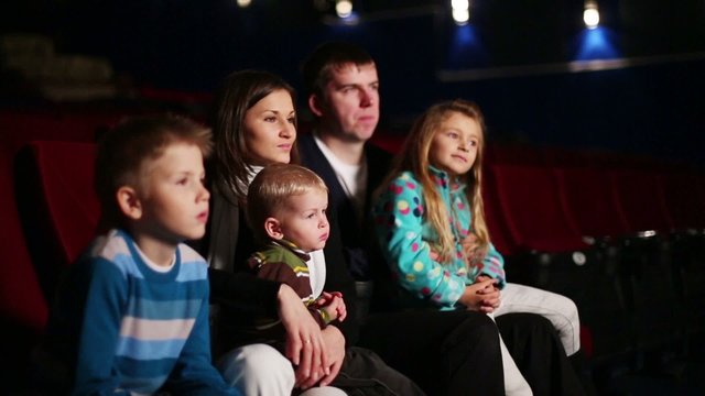 Young man and woman with three children watching a movie