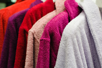 Colored terry bathrobes hanging on the store trempel - obrazy, fototapety, plakaty