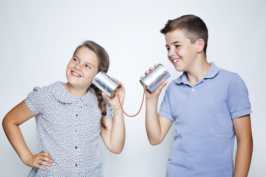 Kids using a can as telephone against gray background