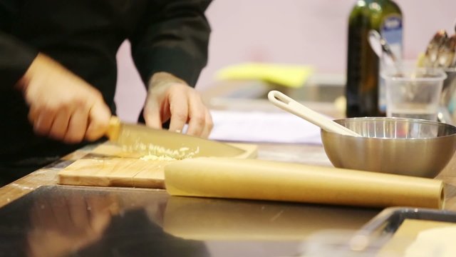Male hands cut garlic by big knife into small pieces